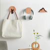 A collection of decorative wooden animal hooks and a canvas tote bag mounted on a white wall.