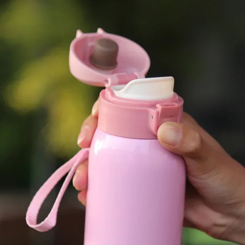 A hand holds a pink vacuum insulated coffee mug with a lid open, showing the stainless steel interior.