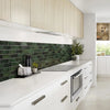 Modern kitchen featuring light wood cabinetry, a dark green subway tile backsplash, and white countertops.