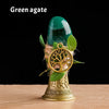 A green agate gemstone is displayed in a brass tree of life chime with green leaves.