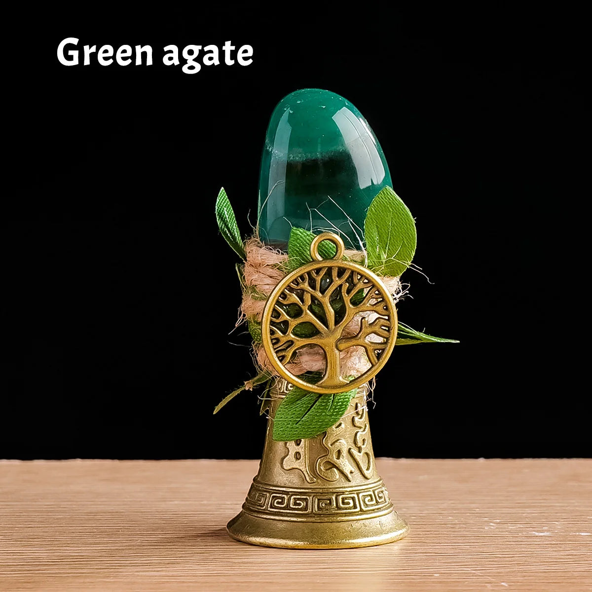 A green agate gemstone is displayed in a brass tree of life chime with green leaves.
