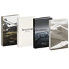 A set of four decorative faux books in neutral tones featuring landscapes like moss, neutral, noir, and sand.