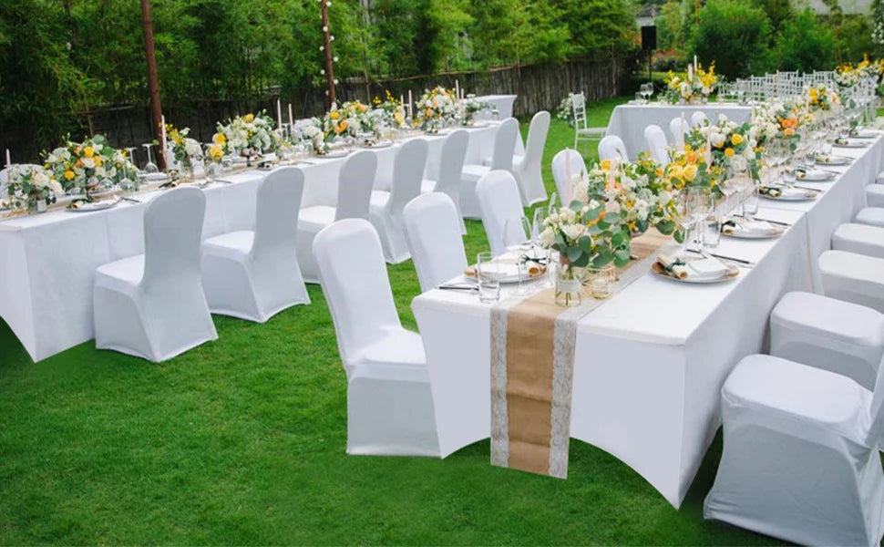 White stretch fitted spandex table covers with floral centerpieces set up for an outdoor event.