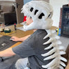 A person wearing a white 3D dinosaur skeleton plush costume for kids, showing the upper torso and head.