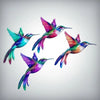A vibrant, iridescent hummingbird in shades of purple, green, and magenta, displayed as wall art.