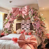 A pink satin bow with long tulle drape decorates a bed with floral arrangements for an event.