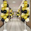 A display of gold and black balloons arranged in tall columns on white stands.