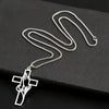 Silver hollow prayer hands cross pendant necklace displayed on a black surface.