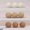 A set of four smooth, spherical cake toppers in a light beige color.