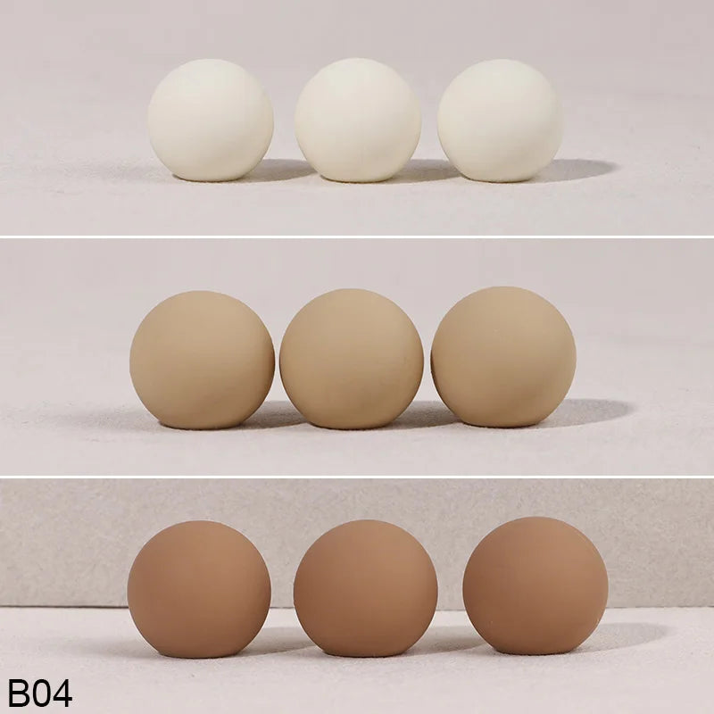 A set of four smooth, spherical cake toppers in a light beige color.