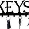 Black decorative metal wall-mounted key holder with seven hooks and various keys.