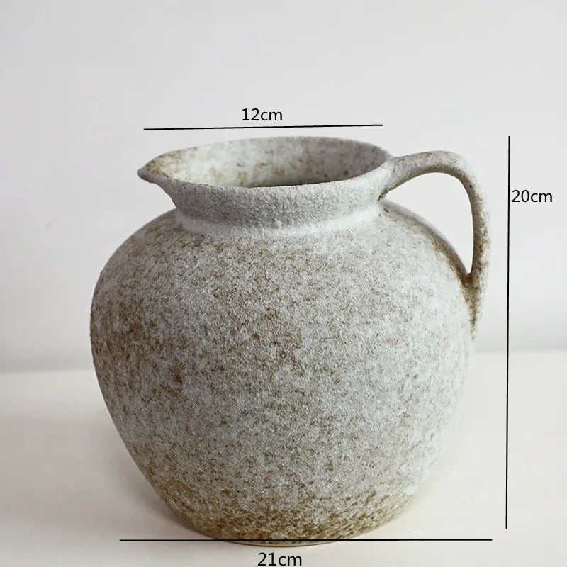 A speckled, round ceramic vase with a handle and spout, shown against a white background.