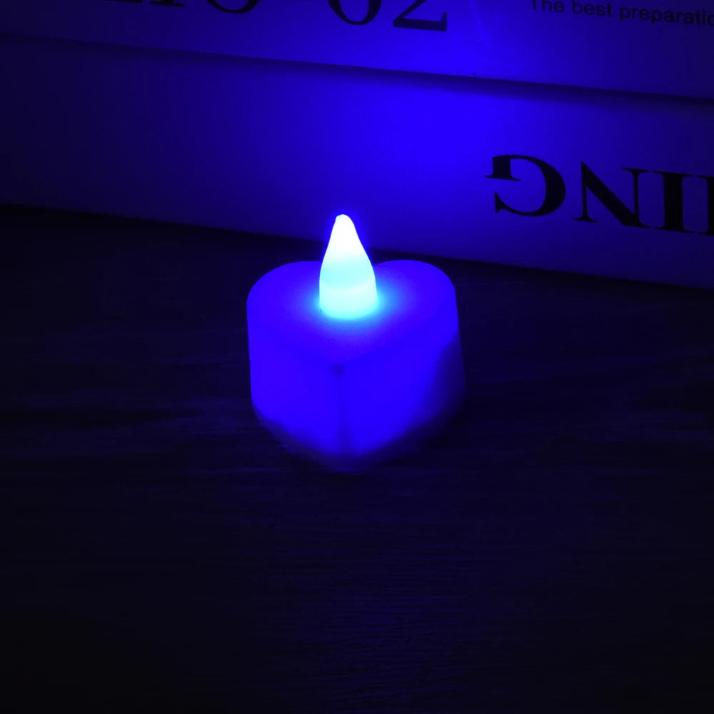 A glowing blue heart-shaped flameless LED tealight candle resting on a dark wooden surface.