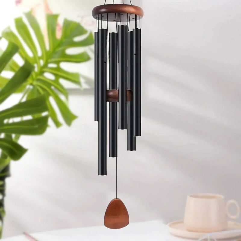 Carillon suspendu en tubes métalliques sombres et dessus en bois, exposé sur fond lumineux.