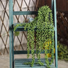 Artificial hanging succulent vine with green leaves displayed on a wooden stand.