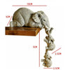 A resin figurine set of a large elephant hugging a baby elephant, displayed on a wooden base.