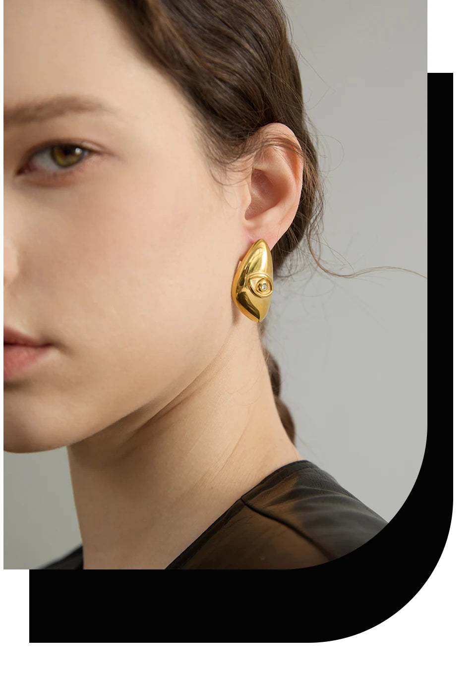 A close-up of a woman's ear showing a gold geometric stud earring.