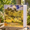A photo album featuring a painting of rolling hills and a stone building under bright sunlight.