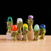 A collection of natural crystal stones, including green, white, and purple, mounted on gold-toned stands with leafy accents.