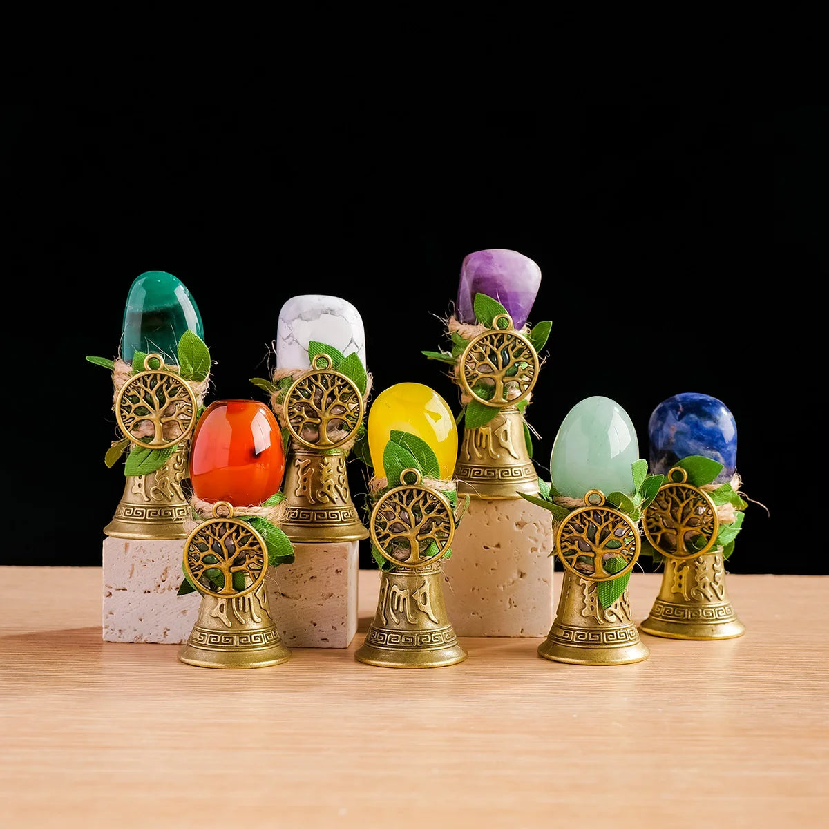 A collection of natural crystal stones, including green, white, and purple, mounted on gold-toned stands with leafy accents.
