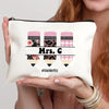 A cream-colored canvas makeup bag with pink and black plaid patterns and the text Mrs C