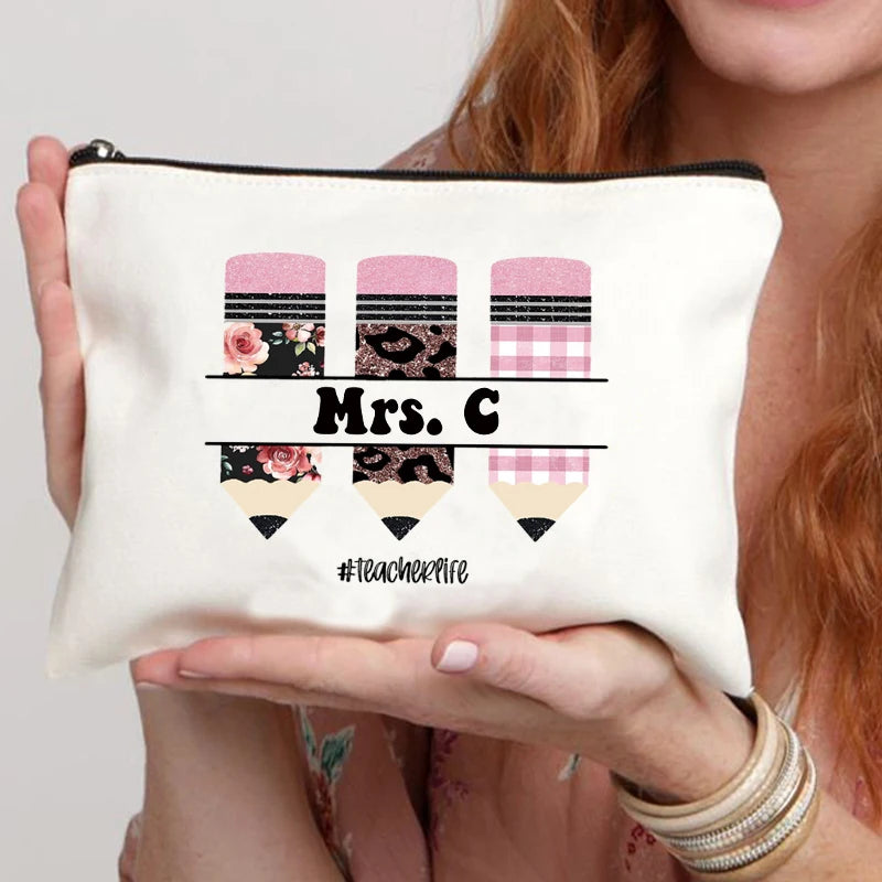 A cream-colored canvas makeup bag with pink and black plaid patterns and the text Mrs C