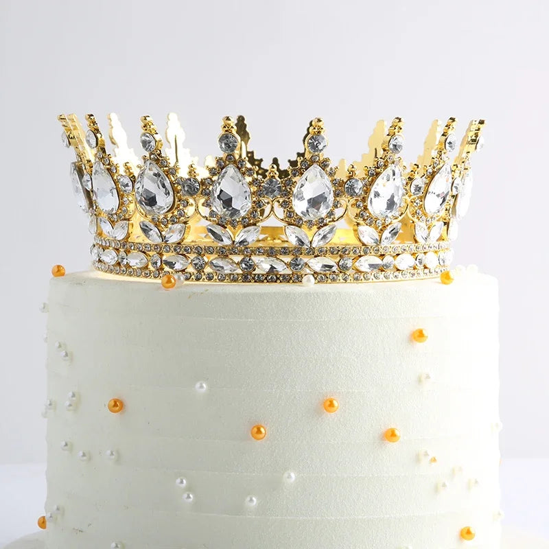 Gâteau à étages blanc décoré d'une couronne en cristal doré et de perles oranges éparpillées.