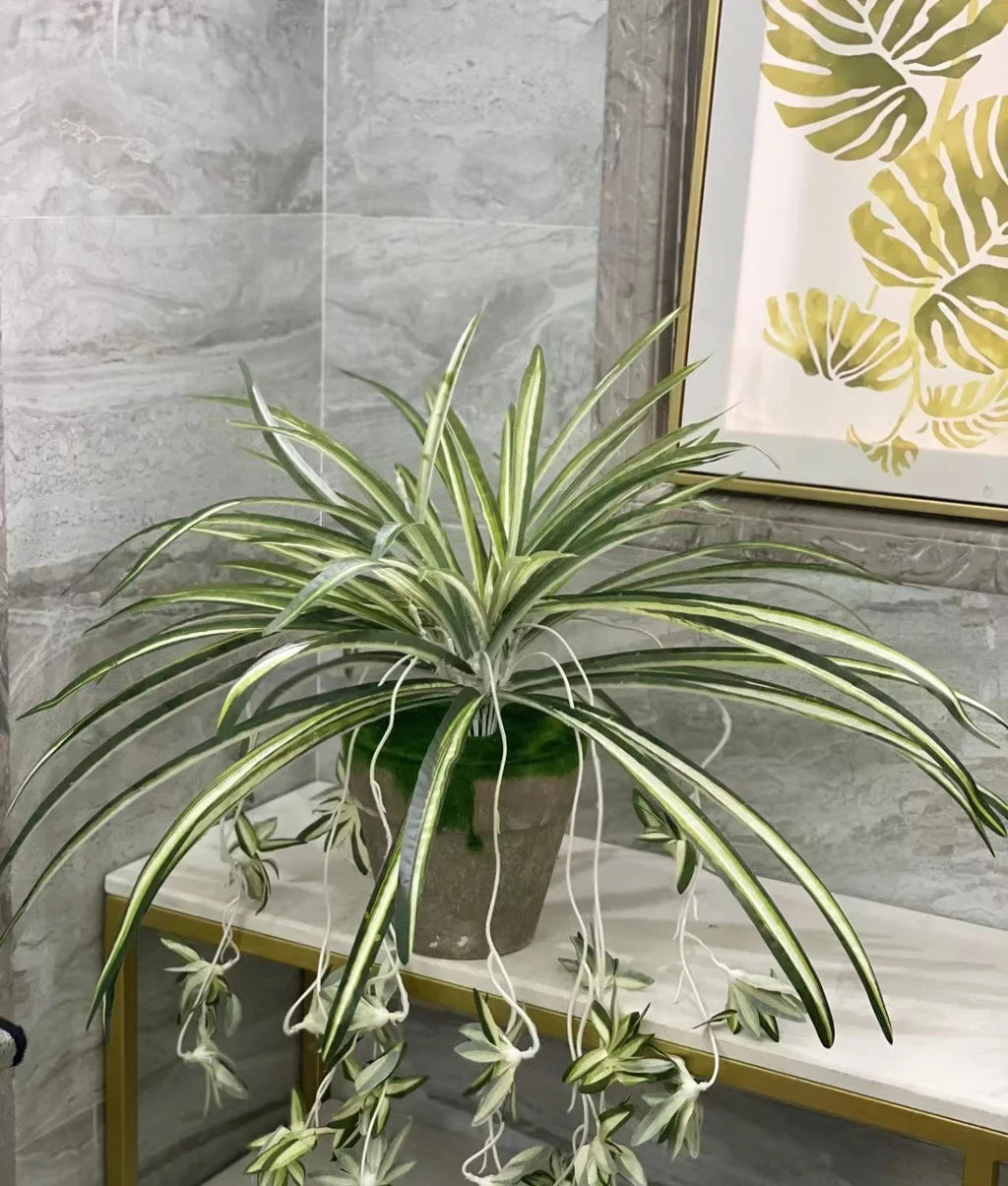 Artificial chlorophytum branch with variegated green and white leaves displayed in a potted plant on a shelf.