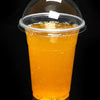 A tall glass filled with bright orange juice or beverage, viewed from above against a dark background.