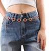 A close-up of denim jeans featuring a red crystal waist chain detail.