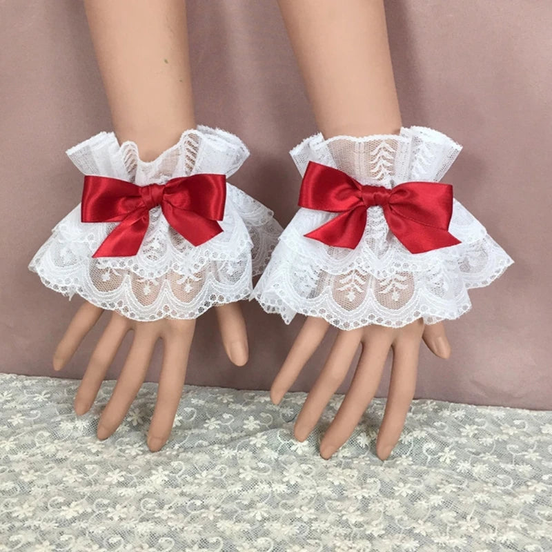 White ruffled lace wrist cuffs with red satin bow accents displayed on a mannequin hand.