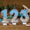 Glitter number cake toppers shaped like 1, 2, and 3 with starfish designs on a brown background