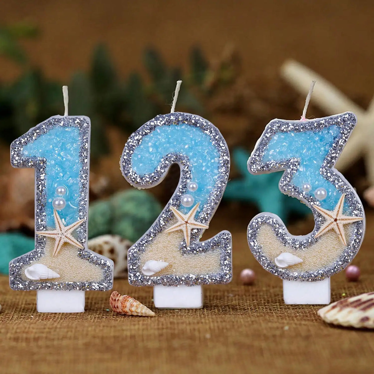 Glitter number cake toppers shaped like 1, 2, and 3 with starfish designs on a brown background
