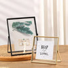 A modern metal and acrylic photo frame with a green leaf design displayed on a wooden surface.