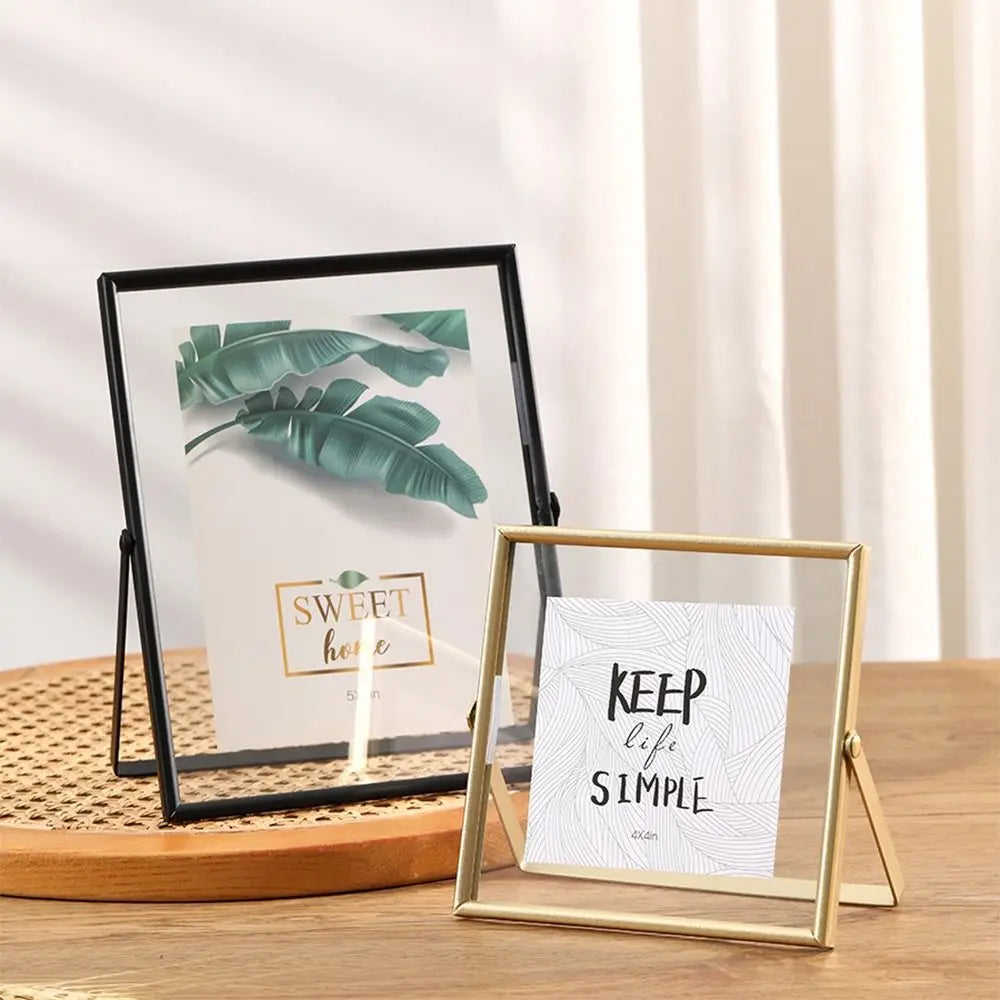 A modern metal and acrylic photo frame with a green leaf design displayed on a wooden surface.