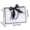A set of elegant black and white gift bags tied with black ribbon bows