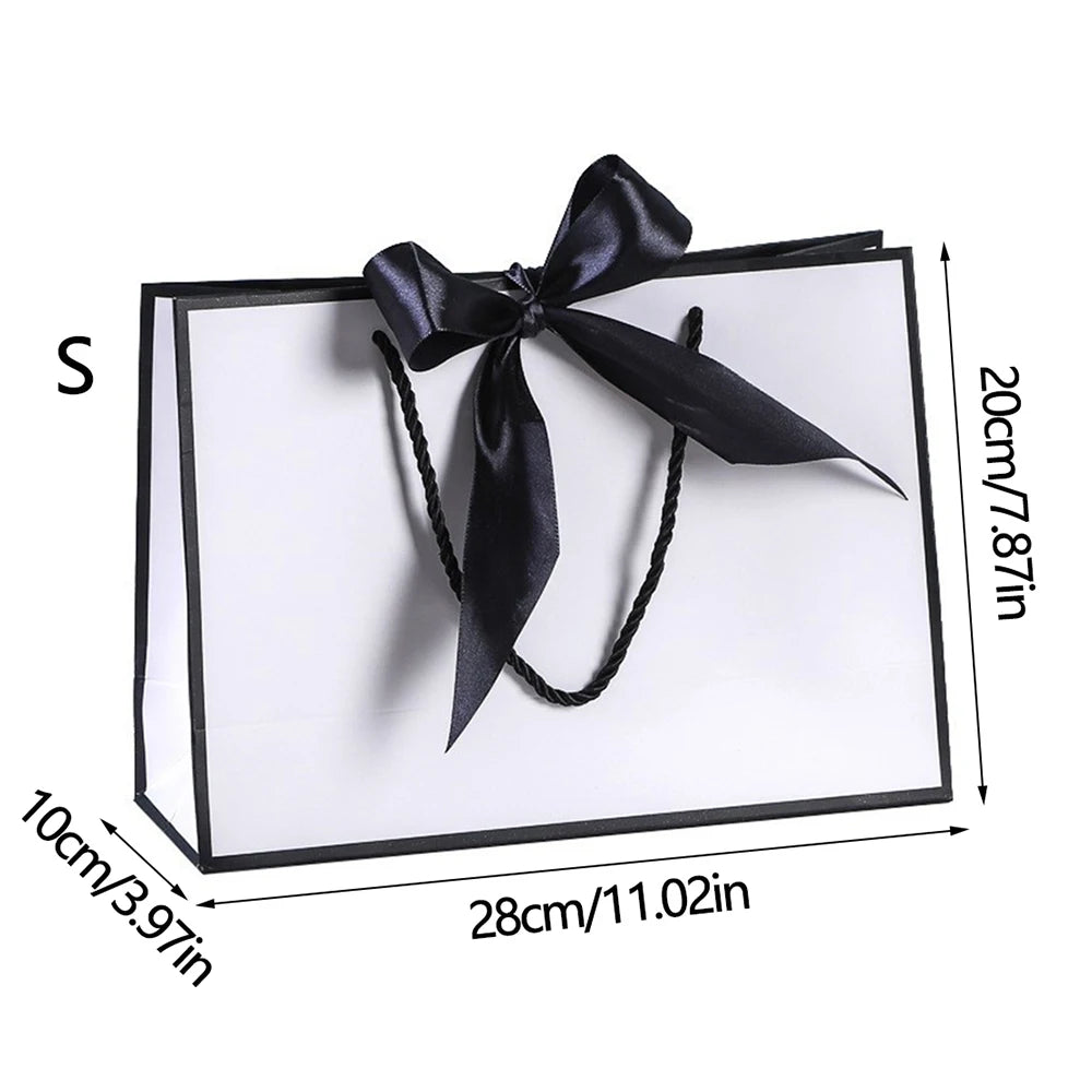 A set of elegant black and white gift bags tied with black ribbon bows
