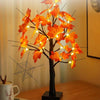 Installation lumineuse d'un arbre de bouleau noir artificiel avec des feuilles de érable orange vif et un filet d'araignée dé