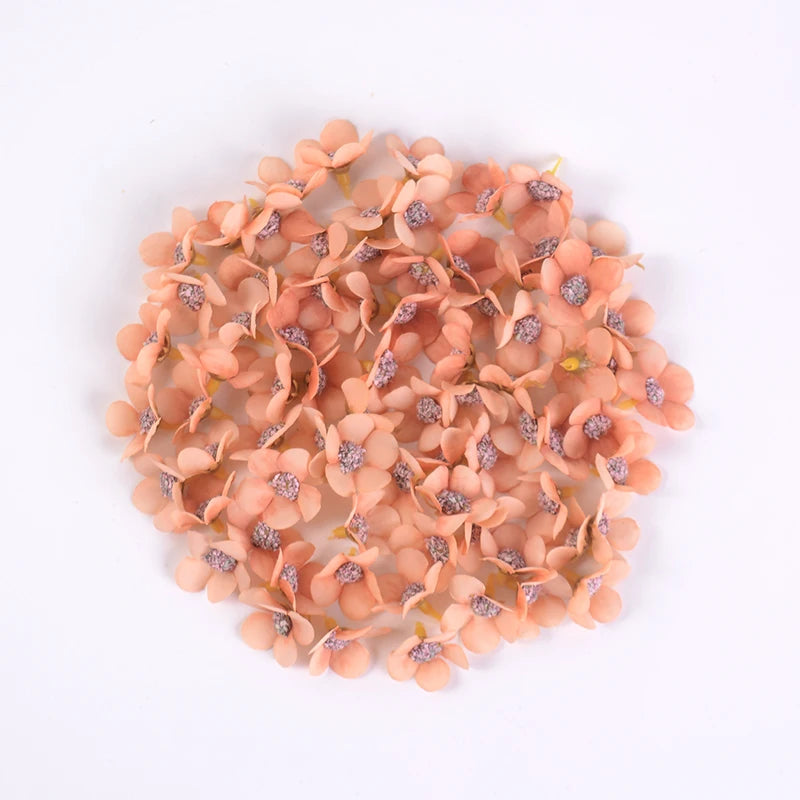 A pile of small, peach-colored silk artificial flower heads used for weddings and crafts.