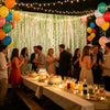 A festive outdoor party setup featuring sage green wavy foil fringe curtain streamers and balloons.