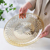 A hand is holding a clear acrylic serving plate with a geometric pattern, ready for use.