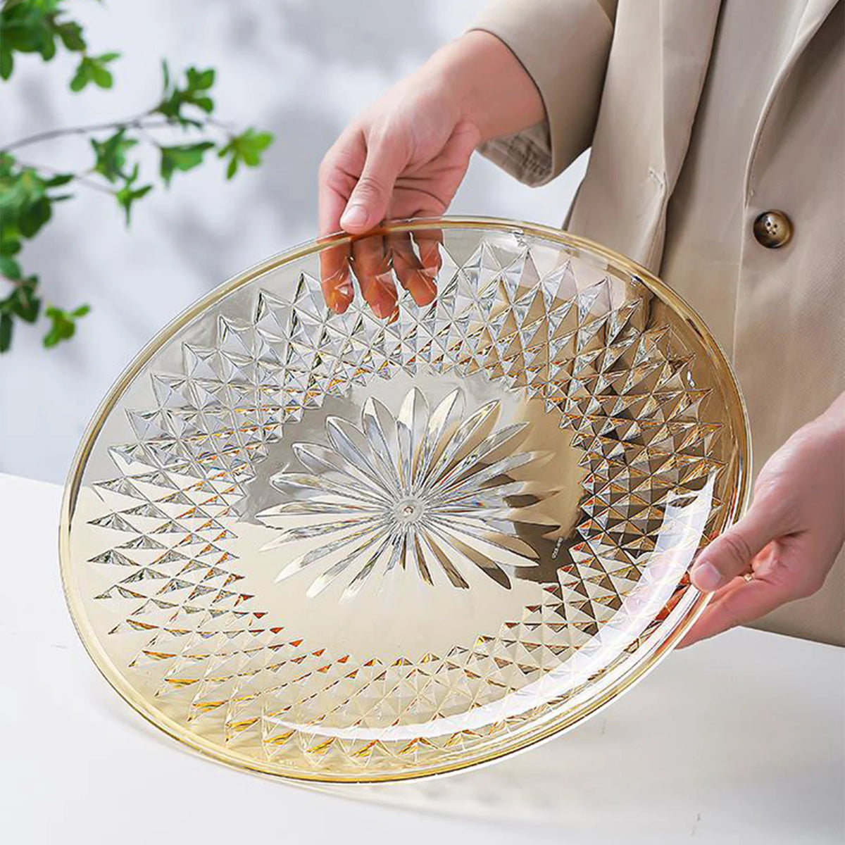 A hand is holding a clear acrylic serving plate with a geometric pattern, ready for use.
