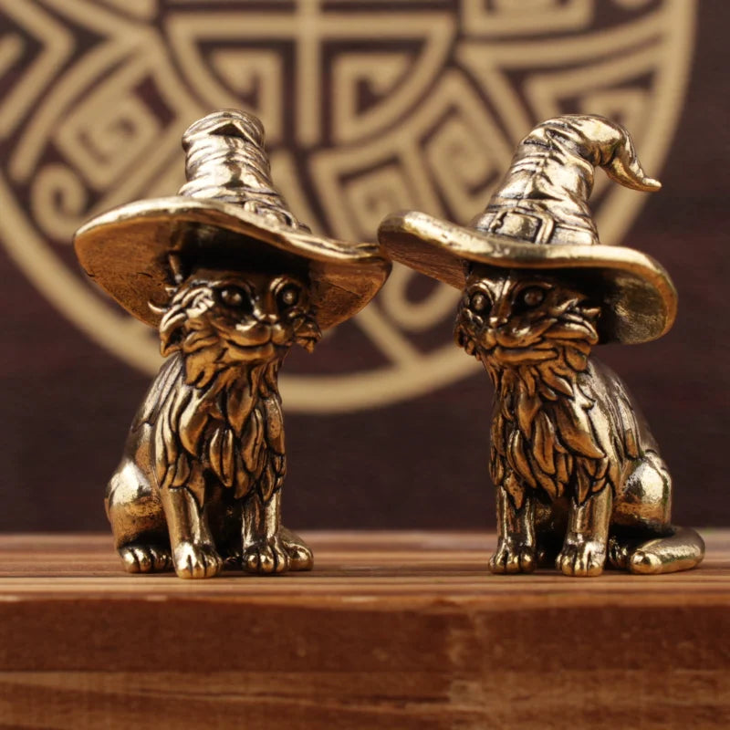 Une paire de statuettes de chats en laiton vintage, ressemblant à des chapeaux de sorcière, sont exposées sur une surface en 