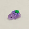 A small purple resin charm shaped like a turtle with green fruit on its back.