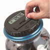 A hand is operating a digital coin counting piggy bank with an LCD display on the top.