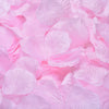 A close-up of pink silk rose petals scattered on a surface.