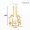 A tall, gold-colored iron hollow vase with a cylindrical glass insert and a circular wire base.