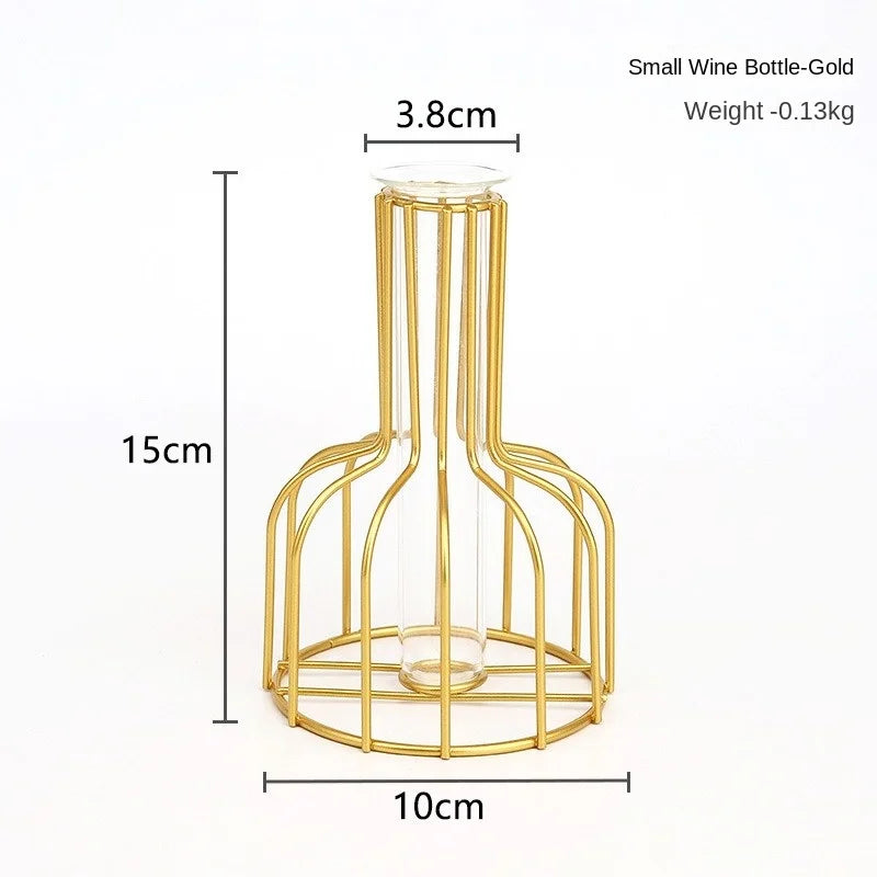 A tall, gold-colored iron hollow vase with a cylindrical glass insert and a circular wire base.