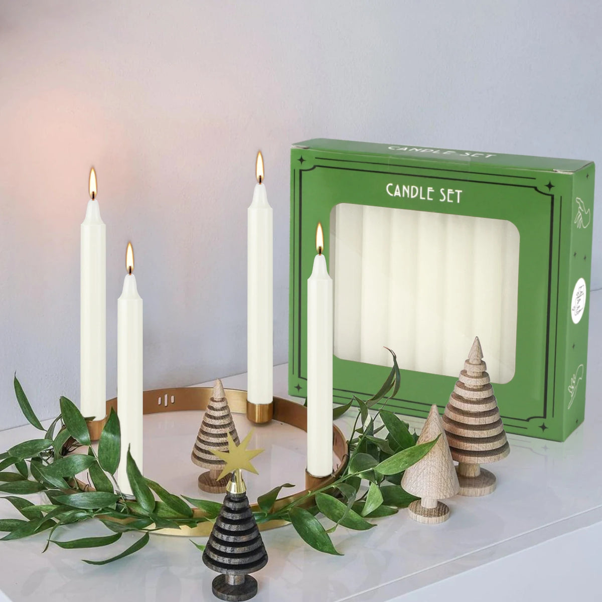 A set of ivory white drip-free stick candles displayed in front of a green box.