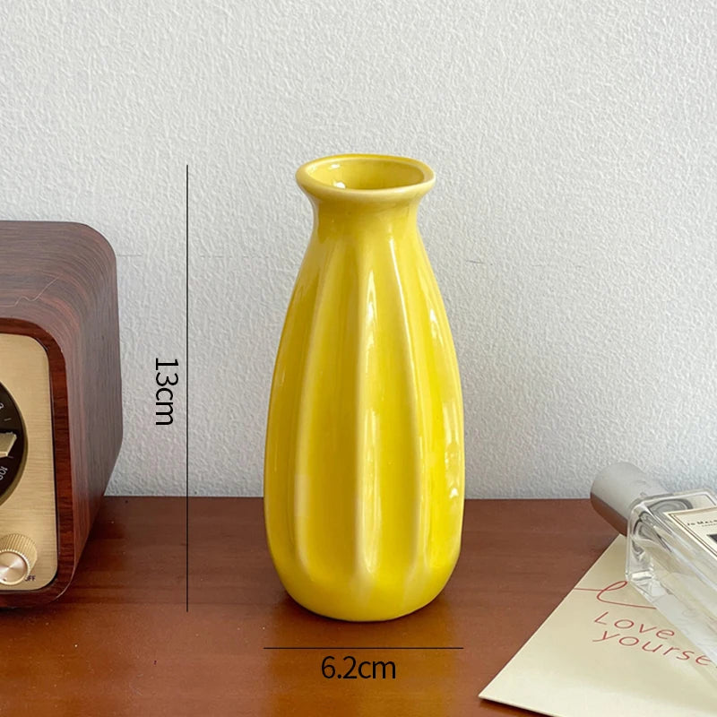 A bright yellow ceramic bud vase sitting on a wooden surface.